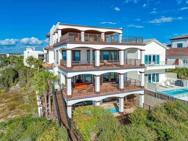 rear view of house with stucco siding and a balcony