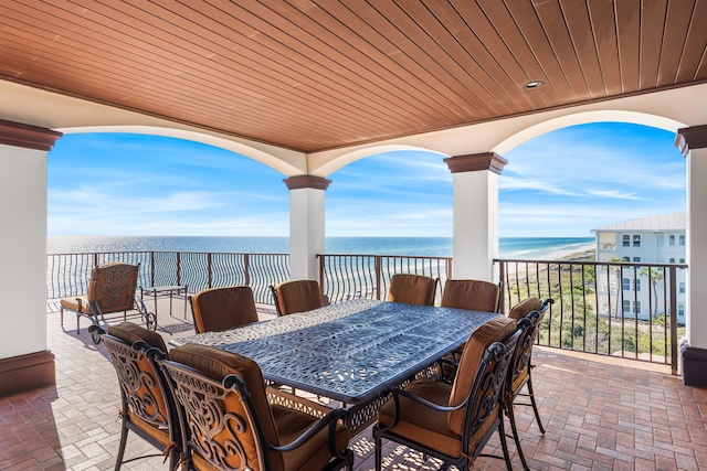 view of patio / terrace with outdoor dining area, a water view, and a beach view