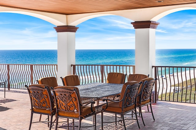 view of patio with a beach view, a balcony, and a water view