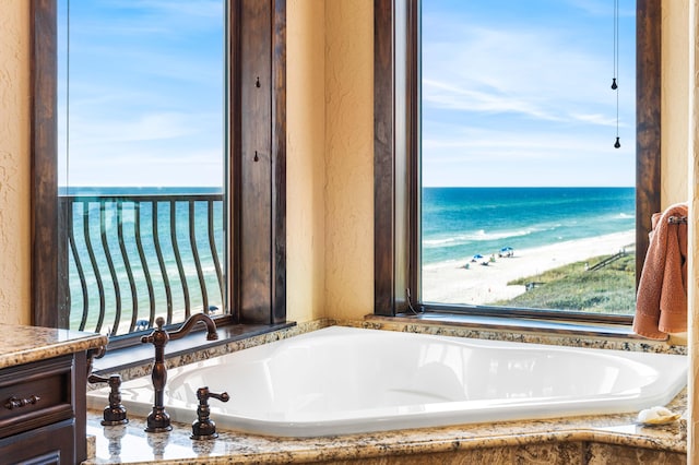 bathroom featuring a bath, a textured wall, and a water view