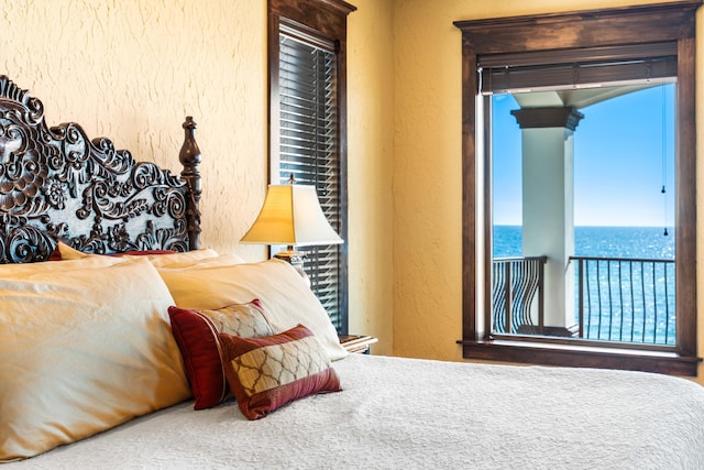 bedroom with a water view and a textured wall