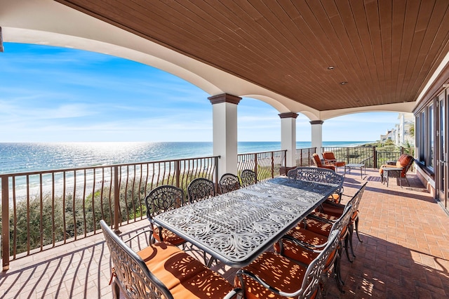 view of patio with outdoor dining area, a water view, and a view of the beach