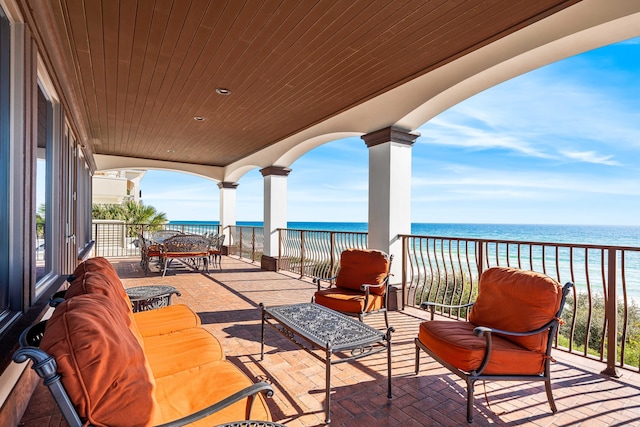 view of patio with a beach view, outdoor lounge area, a balcony, and a water view