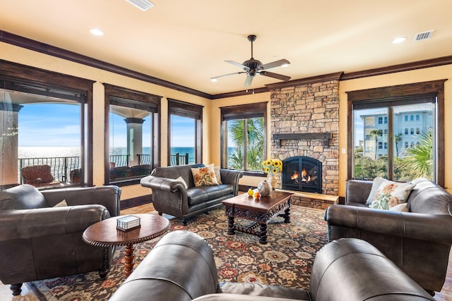 living area featuring visible vents, crown molding, ceiling fan, a stone fireplace, and recessed lighting