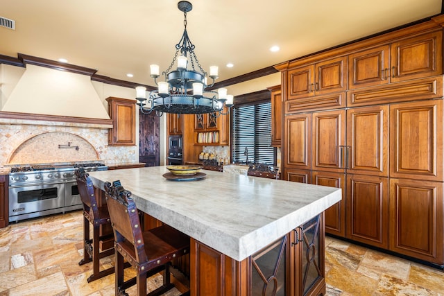 kitchen with premium range hood, stone tile floors, a center island, stainless steel appliances, and a chandelier