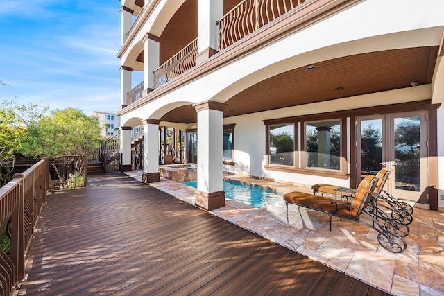 wooden deck featuring a patio and a pool with connected hot tub