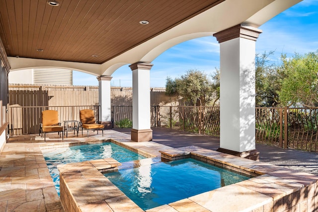 view of pool with a patio area, fence, and a pool with connected hot tub