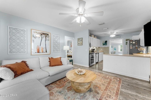 living room with ceiling fan and dark wood-type flooring