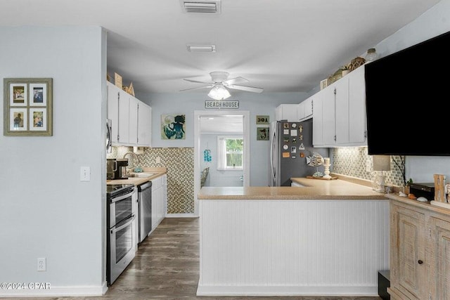 kitchen featuring white cabinetry, dark hardwood / wood-style floors, backsplash, kitchen peninsula, and appliances with stainless steel finishes