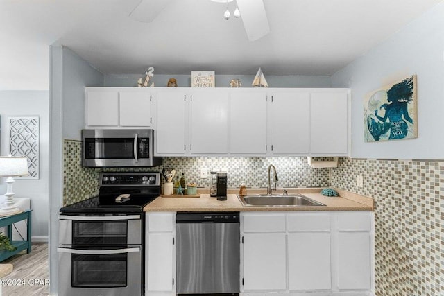 kitchen featuring tasteful backsplash, stainless steel appliances, sink, white cabinets, and light hardwood / wood-style floors