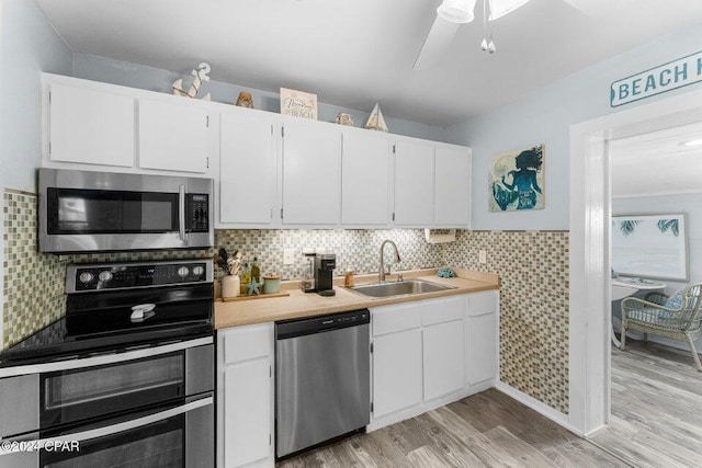 kitchen with white cabinetry, sink, tasteful backsplash, light hardwood / wood-style flooring, and appliances with stainless steel finishes