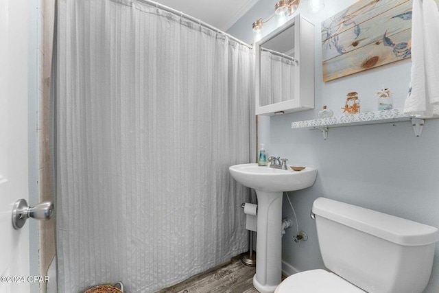 bathroom featuring hardwood / wood-style floors, toilet, ornamental molding, and a shower with shower curtain