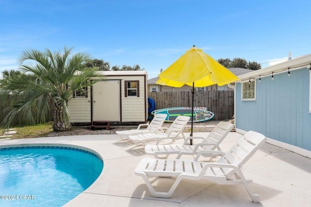 view of pool featuring a storage unit and a patio area