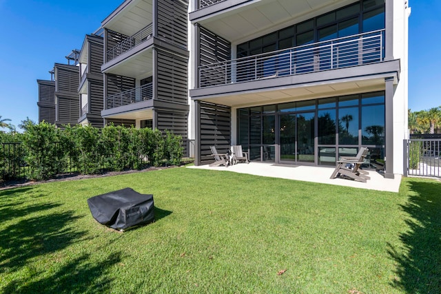 rear view of house with a lawn, a patio area, and a balcony