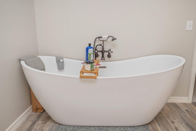 bathroom with a tub to relax in and hardwood / wood-style flooring