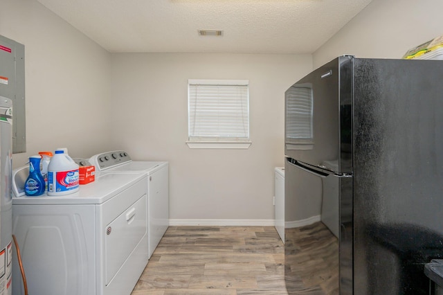 washroom with washer and dryer, a textured ceiling, and light hardwood / wood-style floors