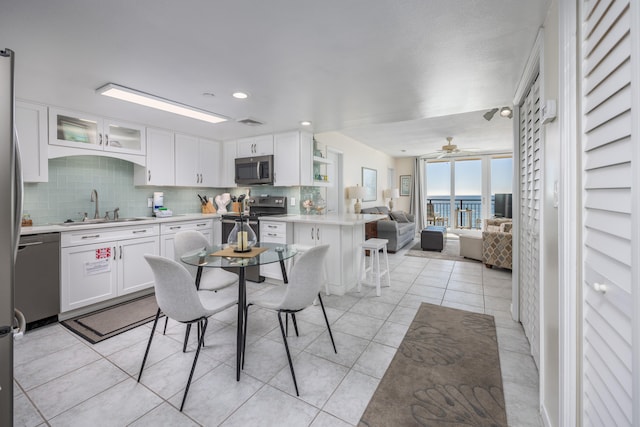 kitchen with stainless steel appliances, white cabinetry, sink, and a breakfast bar area