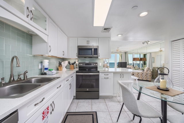 kitchen with light tile patterned flooring, appliances with stainless steel finishes, sink, white cabinets, and backsplash