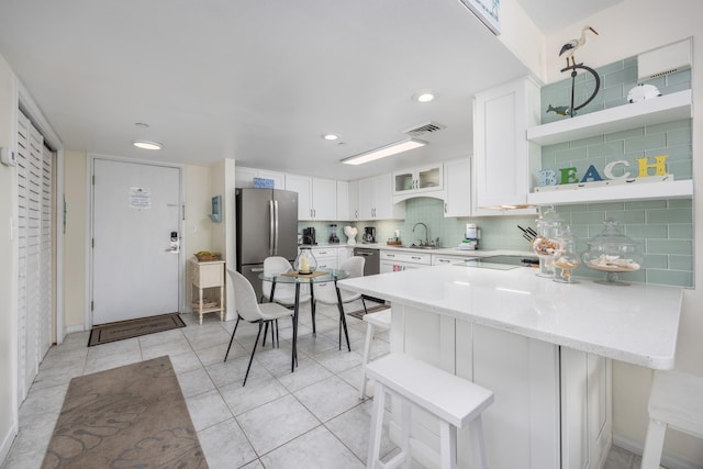 kitchen with stainless steel appliances, white cabinetry, a breakfast bar area, and kitchen peninsula