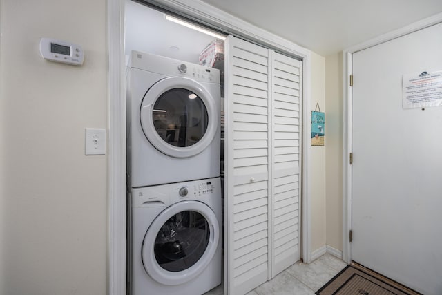 laundry room with stacked washing maching and dryer and light tile patterned floors