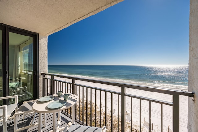 balcony featuring a view of the beach and a water view