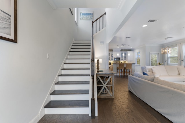 staircase featuring ornamental molding, wood-type flooring, and a chandelier