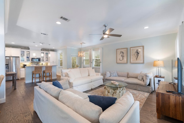 living room with ceiling fan with notable chandelier, ornamental molding, and dark hardwood / wood-style floors