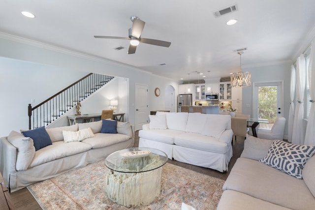 living room with ceiling fan with notable chandelier, ornamental molding, and dark hardwood / wood-style floors