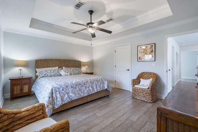 bedroom with hardwood / wood-style flooring, a raised ceiling, ceiling fan, and ornamental molding