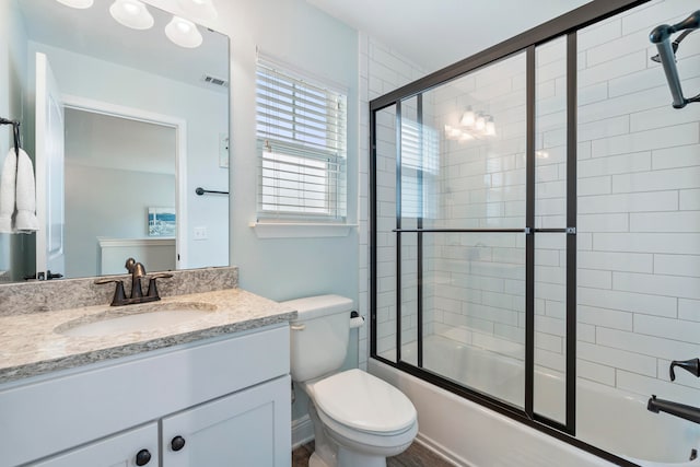 full bathroom featuring shower / bath combination with glass door, vanity, and toilet