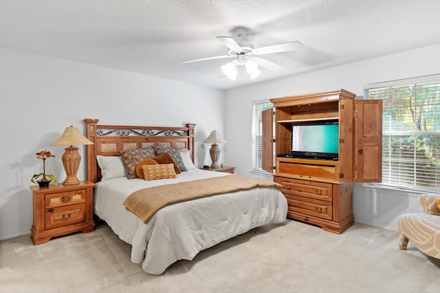 bedroom featuring a textured ceiling, ceiling fan, and light carpet