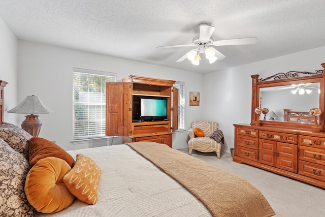 carpeted bedroom with ceiling fan and a textured ceiling