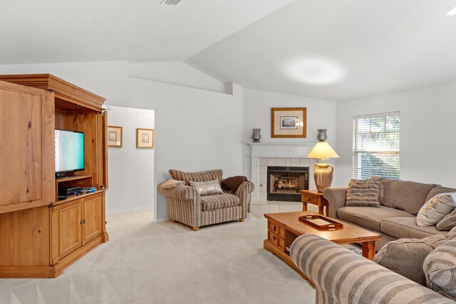 carpeted living room featuring a tiled fireplace and vaulted ceiling