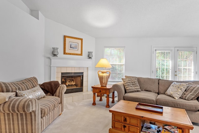 carpeted living room featuring a tiled fireplace, a textured ceiling, and vaulted ceiling