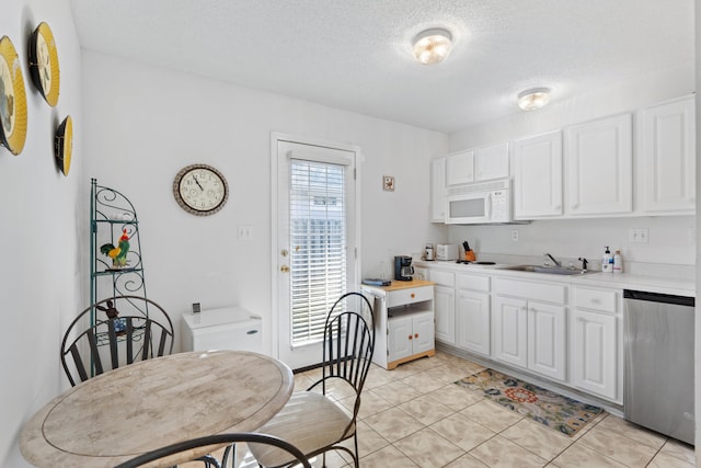 kitchen featuring sink, stainless steel dishwasher, a textured ceiling, light tile patterned flooring, and white cabinetry