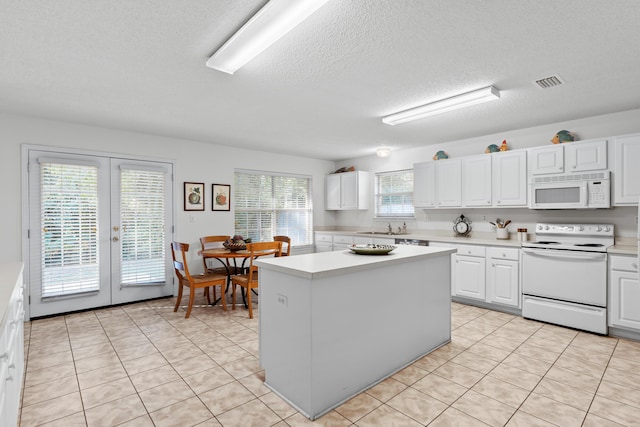 kitchen featuring white cabinets, a healthy amount of sunlight, a kitchen island, and white appliances