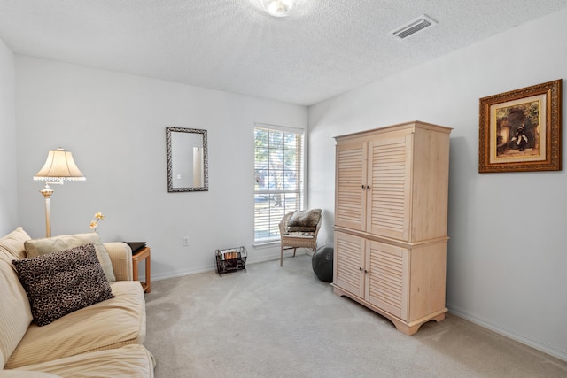 living area with light carpet and a textured ceiling