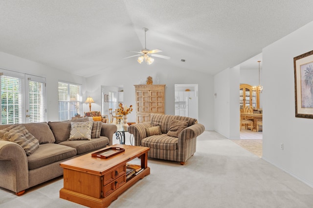 carpeted living room featuring ceiling fan with notable chandelier, a textured ceiling, and vaulted ceiling