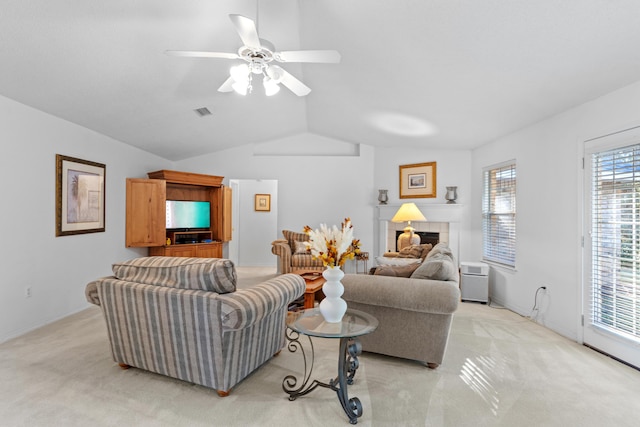 living room featuring a tiled fireplace, light carpet, ceiling fan, and vaulted ceiling