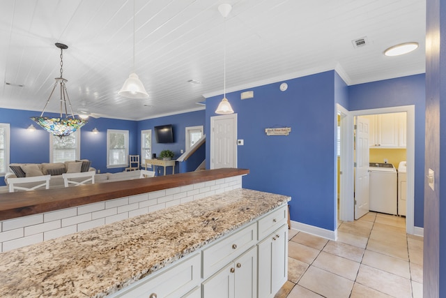 kitchen featuring white cabinetry, light stone counters, decorative light fixtures, light tile patterned floors, and washer and dryer