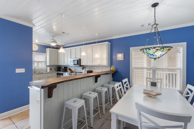 kitchen with kitchen peninsula, pendant lighting, stainless steel appliances, and white cabinets