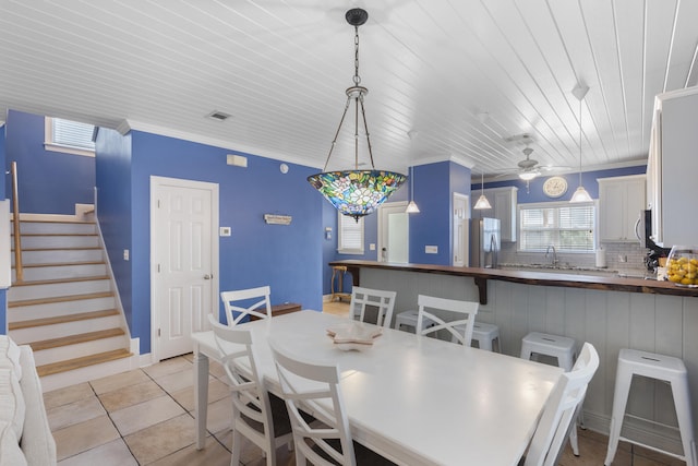 dining area featuring ceiling fan, sink, crown molding, light tile patterned floors, and wood ceiling