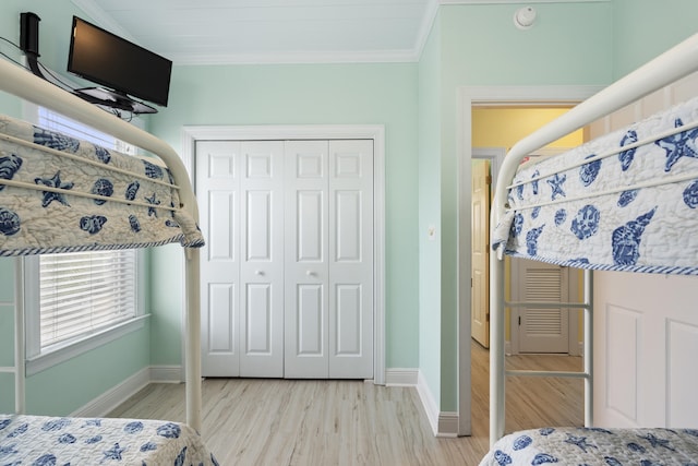 bedroom with light hardwood / wood-style floors, a closet, and crown molding