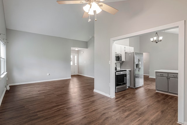 unfurnished living room featuring dark hardwood / wood-style flooring, a wealth of natural light, and ceiling fan with notable chandelier