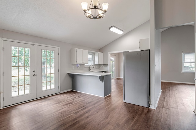 kitchen with french doors, kitchen peninsula, a breakfast bar, white cabinetry, and stainless steel fridge