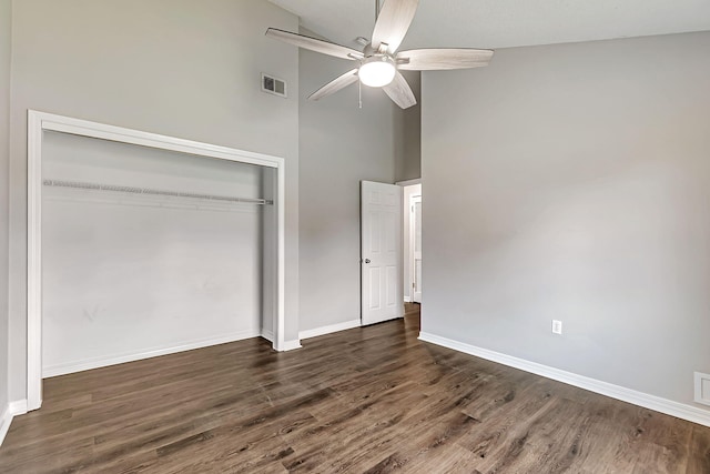 unfurnished bedroom with a closet, wood finished floors, baseboards, a towering ceiling, and ceiling fan
