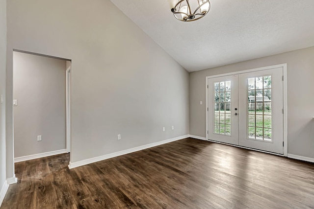 spare room with vaulted ceiling, dark wood finished floors, french doors, a chandelier, and baseboards
