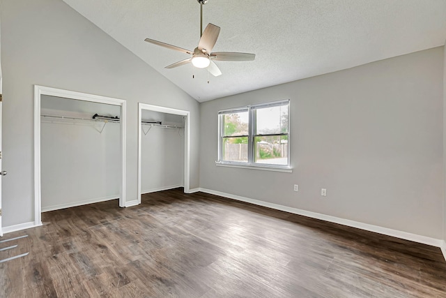 unfurnished bedroom featuring two closets, wood finished floors, vaulted ceiling, baseboards, and ceiling fan