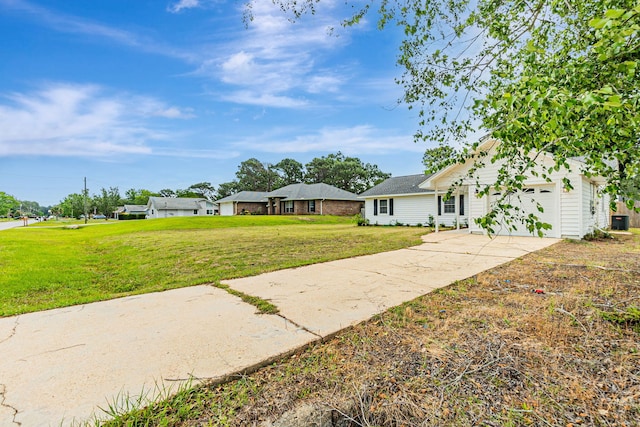 view of front facade with a front yard, concrete driveway, an attached garage, and central air condition unit