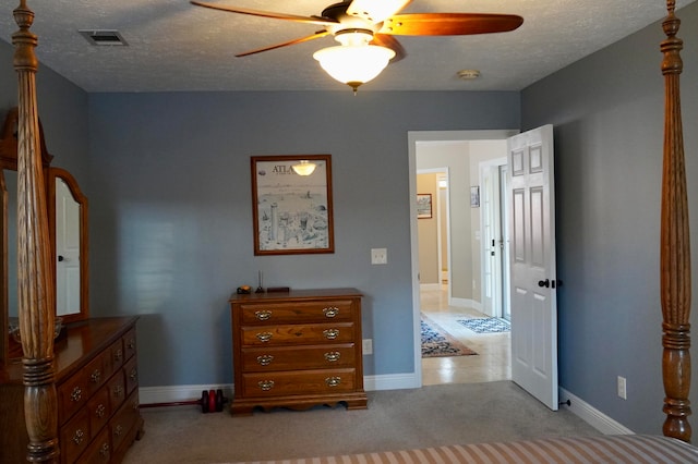 bedroom with a textured ceiling, light colored carpet, and ceiling fan